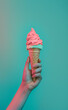Summer, hot weather copy space. Hand holding a soft ice cream cone against pastel teal background.
