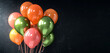 Festive balloons in a blend of orange, lime green, and hot pink, creating a lively contrast against a pure black background