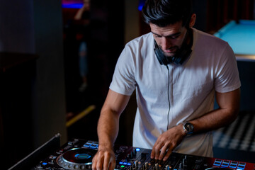 DJ musician man playing and mixing a song with a turntable and headphone. Dance party. excited dj sound device operator with headphones by dancing at club. concept of entertainment in  nightlife.