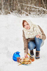 Wall Mural - Teenage girl opens glass jar with honey near blue jug, glass cup with beverage, plate with pancakes on snow