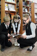 © Pavel Losevsky - Three students, two girls and boy, sat down on his haunches and looked at book, which keeps older girl