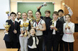 © Pavel Losevsky - Group portrait of students standing in row in classroom, on background of board, hold sports awards - cups, statuettes