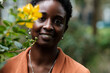 © Jorge Elizaquibel - Smiling black woman looking at camera beside blurred flower.