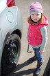 © Pavel Losevsky - Portrait of a little girl in pink waistcoat and striped hat with socket wrench in hands near car