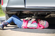 © Pavel Losevsky - Little girl in pink waistcoat and striped hat lying under car with socket wrench in hands
