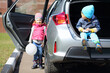 © Pavel Losevsky - Little boy in yellow glasses sitting in open trunk of foreign car and girl with white balloon standing at the open door