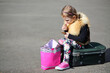 © Pavel Losevsky - Little girl sitting on suitcase in middle of road and painting lips with lipstick