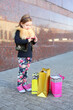 © Pavel Losevsky - Little girl standing with pink phone and shopping bags near granite wall