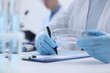 © New Africa - Laboratory worker holding petri dish with blood sample while working at white table, closeup