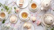 A sophisticated tea party setup viewed from above, featuring fine bone china teacups rimmed with gold, a teapot and plates of delicate macarons. 