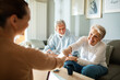 © Marko Geber - Elderly couple greeting a visitor at home with a handshake and smiling