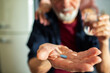 © Marko Geber - Senior man holding medication pill with glass of water in background
