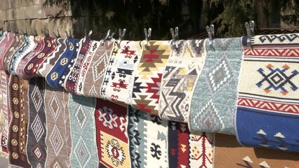 Wall Mural - A variety of patterned Georgian carpets hung for sale along an ancient city street.