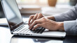 © Studio Nova - Close-up of a person's hands typing on a laptop keyboard, dressed in a suit, indicating a professional setting or business work