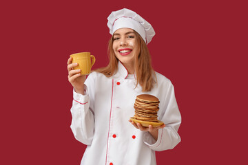 Sticker - Happy young female chef with tasty pancakes and cup of tea on red background