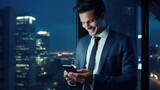 Fototapeta  - Smiling man in a business suit is looking at his smartphone against office background