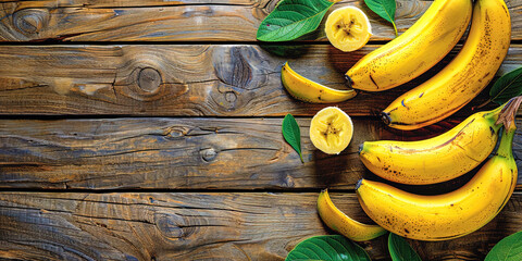 Wall Mural - Bananas, folded in a group on a wooden table, with green leaves and a yellow peel, against a