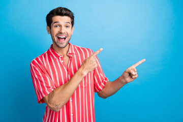 Wall Mural - Photo of cool impressed guy wear red shirt open mouth pointing two fingers empty space isolated blue color background