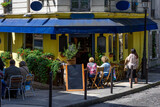 Fototapeta Paryż - Cozy street with tables of cafe in quarter Montmartre in Paris, France. Architecture and landmark of Paris. Cozy Paris cityscape.