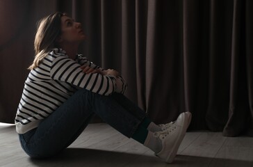 Poster - Sad young woman sitting on floor indoors, space for text