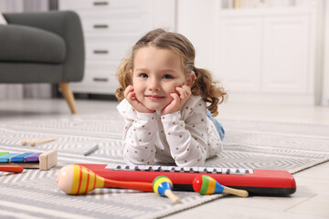 Wall Mural - Little girl playing with toy musical instruments at home