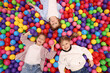 © New Africa - Happy little kids lying on many colorful balls, top view
