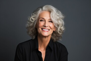 Portrait of smiling senior businesswoman with grey hair against grey background