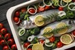 Raw fish with lemon in baking dish and vegetables on black wooden table, flat lay