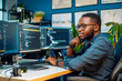 Portrait of young African-American programmer sitting at desk in software development studio
