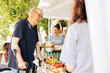 © DC Studio - Charitable efforts at food drive include helping disadvantaged caucasian old man on crutches with support from volunteers of various ethnicities. Disabled male individual receives humanitarian aid.
