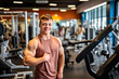 A muscular male bodybuilder with Down syndrome stands proudly in a gym. Concept of inclusivity of the fitness community and adaptive workouts for people with disabilities. Copy space