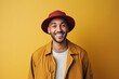 happy african american man in hat and coat on yellow background