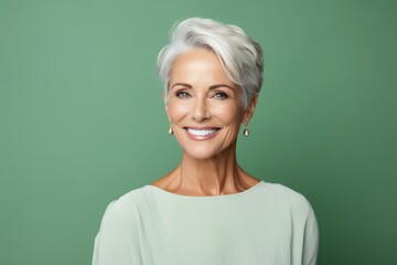 Cheerful senior woman. Portrait of beautiful mature woman smiling and looking at camera while standing against green background