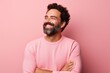 Portrait of happy man with crossed arms looking at camera over pink background