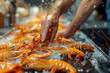 A hand grabbing a rock shrimp from a pile on the table, food culinary