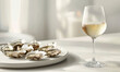 Oysters on a white plate with a glass of white wine, representing gourmet dining and sophistication.