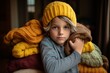 Little girl in a knitted hat and sweater sitting on a sofa in the room.