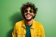 Portrait of a young man with curly hair wearing yellow jacket and green sunglasses
