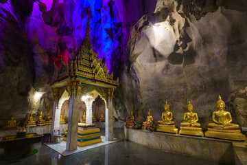 Wall Mural - 
The golden Buddha statues are placed inside a cave at Tham Khao Yoi Temple in Phetchaburi Province. It's a beautiful tourist attraction in Thailand.