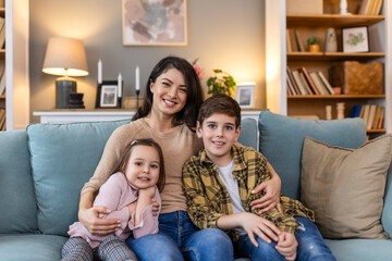 Wall Mural - In the familiar comfort of their living room, a mother, her daughter, and her son gather on the sofa , they create an scene of love and connection, sharing laughter and stories of their family life.
