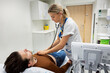 © Johnér - Female doctor checking patient with stethoscope lying on bed in examination room