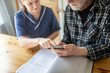 © Johnér - Female nurse teaching mobile phone to elderly man while sitting at home
