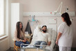 © Johnér - Smiling male patient lying on bed and talking with female doctor in ward