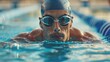 A male swimmer wearing goggles swims through a pool with focused determination