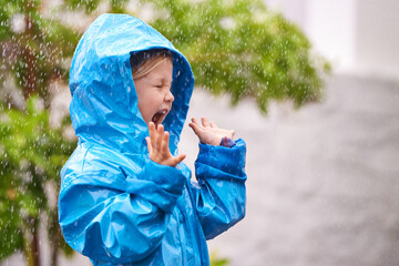 young girl, rain and playing outside in winter, raincoat and playful in the water. joyful, laughing 