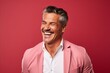 © Iigo - Handsome mature man laughing and looking at camera while standing against red background