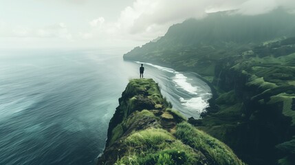 Person on cliff gazes at ocean blending with cloudy sky