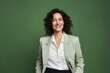 © Iigo - Portrait of a smiling businesswoman looking at camera against green background