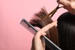 Hairdresser cutting client's hair with scissors on pink background, closeup. Space for text