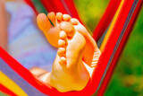 Fototapeta Natura - Close up young beautiful girl sleeping in a hammock with bare feet, relaxing and enjoying a lovely sunny summer day. Safety and happy childhood and leisure concept. Selective focus.